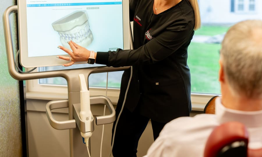 A team member at Sturbridge Orthodontics shows a patient a 3D rendering of their mouth.
